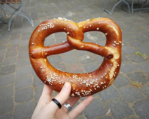 istock Cropped Hand Holding Pretzel On Footpath 660759127