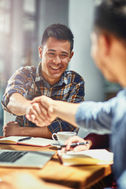 Making connections that count towards his success Shot of two young designers shaking hands together in an office casual clothing stock pictures, royalty-free photos & images