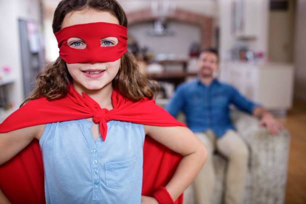 istock Daughter pretending to be a superhero while father sitting on sofa 660778636