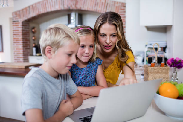 istock Mother and kids using laptop in kitchen 660783708