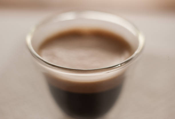 A clear cup of espresso on a table.