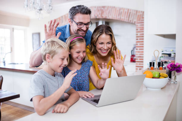 istock Parents and kids waving hands while using laptop for video chat 660788208