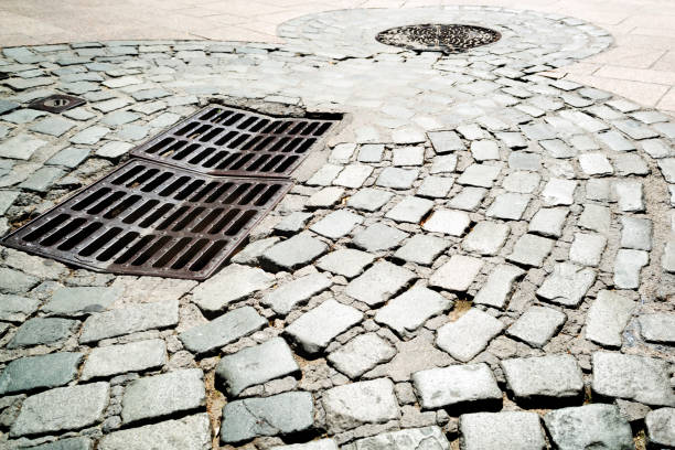 Steel sewer manhole on old cobblestone road
