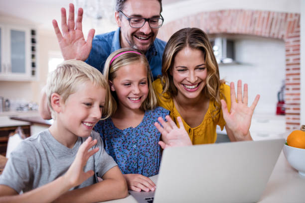 istock Parents and kids waving hands while using laptop for video chat 660790770