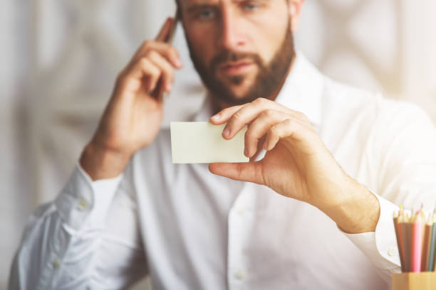 istock Man with phone and business card 660834124