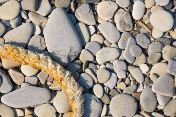 old worn battered marine rope on the pebble beach on a Sunny summer day, top view