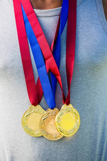 Mid section of athlete posing with gold medals around his neck