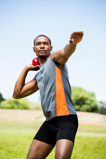 Male athlete about to throw shot put ball in stadium
