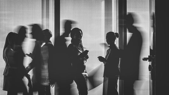 Silhouettes of a group of business people standing or walking in the office building