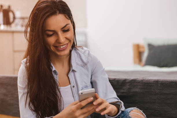istock Girl checking phone. Beautiful relaxed student texting via mobile phone at home. 660897550