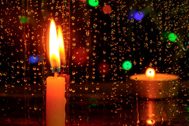 istock Candle stands in front of a window with rain drops. 660905570