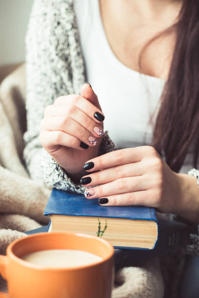 istock Young woman reading book, close-up, on home interior 660922324