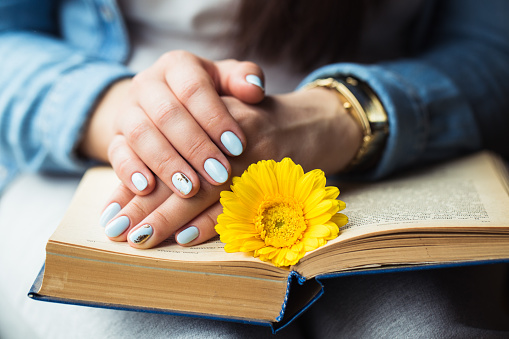 Girl's hands on a book with a yellow flower