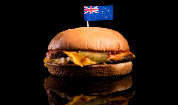 New Zealand flag on top of hamburger isolated on black background stock photo