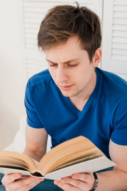 istock Man reading a book sitting on the bed 660963642