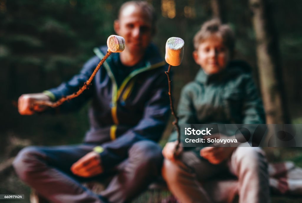 Father and son prepear to bake marshmallow candies on campfire Father and son prepare to bake marshmallow candies on campfire Marshmallow Stock Photo