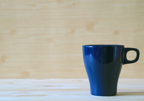 Front view of navy blue mug on the light color wooden table, Background