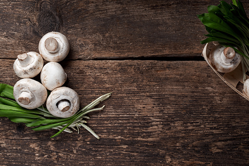 Fresh white mushrooms champignon in brown bowl on wooden background. Top view. Copy space.
