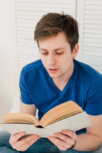 istock Man reading a book sitting on the bed 660983322