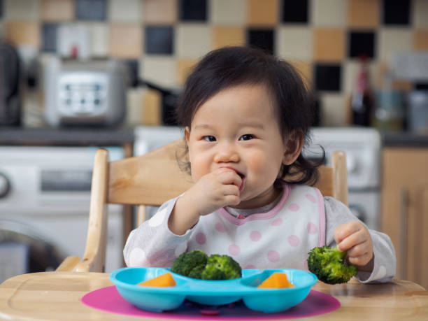 istock baby girl eating vegetable first time 660989922