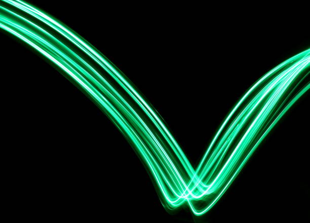 A long exposure photograph of green fairy lights in a V shape design, against a clean black background