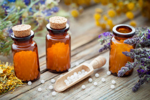 Bottles of homeopathic globules and healing herbs. Homeopathy concept. stock photo