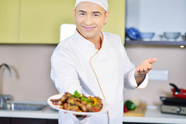istock Cook holding plate with food in welcoming gesture 661013664