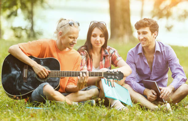 istock group of students with a guitar resting in the Park on a Sunny day 661023404
