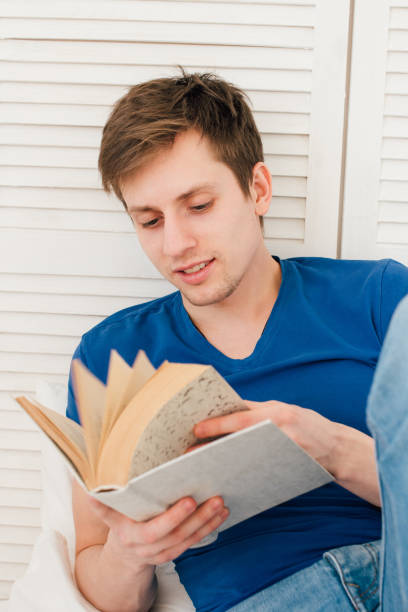 istock Man reading a book sitting on the bed 661030490