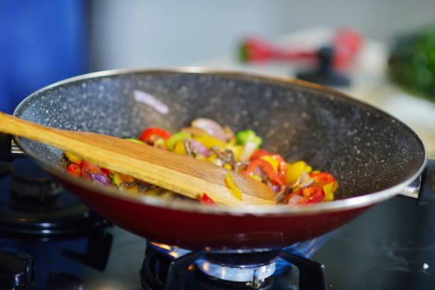 Vegetable ragout in pan, on wooden table on bright background.