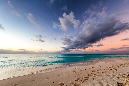 Young woman walking over a beach and leaving her footprints on the sand