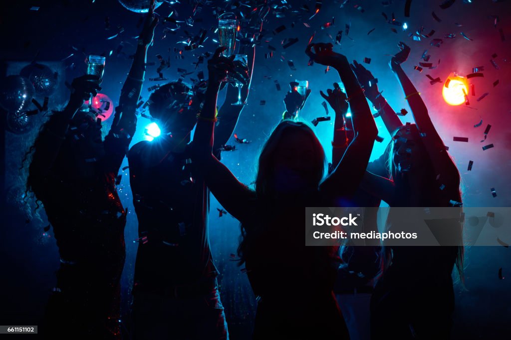 Nightclub party with confetti Silhouette of young people with raised flutes having fun and clubbing Party - Social Event Stock Photo