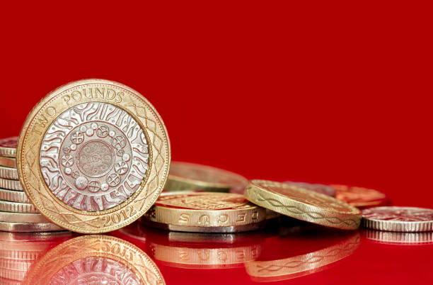monedas británicas sobre fondo rojo brillante - two pound coin fotografías e imágenes de stock