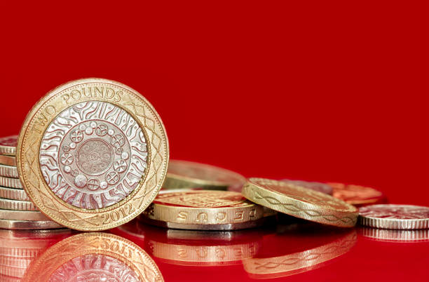 moedas britânicas sobre fundo vermelho brilhante - two pound coin - fotografias e filmes do acervo