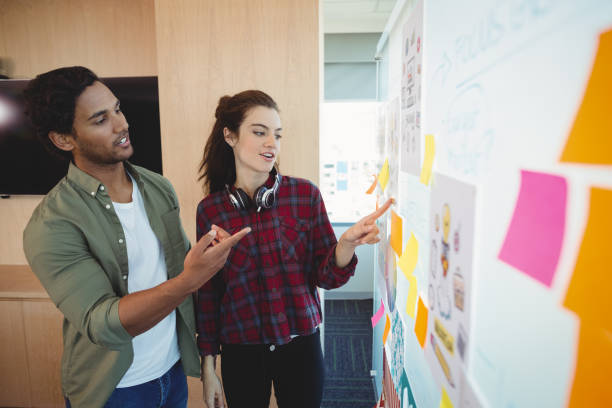 istock Male and female graphic designers discussing over sticky notes 661161480