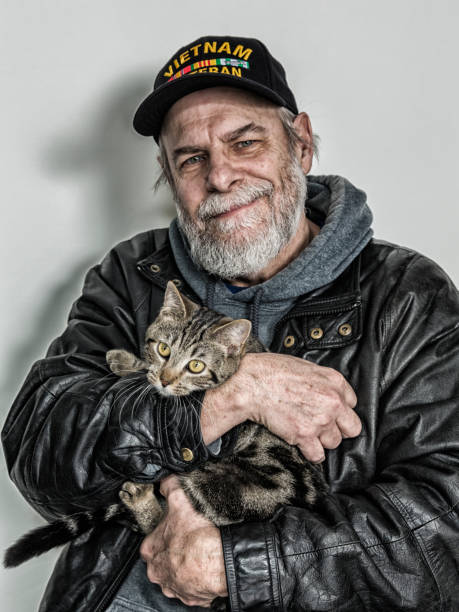 autêntico e.u. da marinha de guerra de vietnã veterano aconchegando curioso de estimação gatinho - men hat leather senior adult - fotografias e filmes do acervo