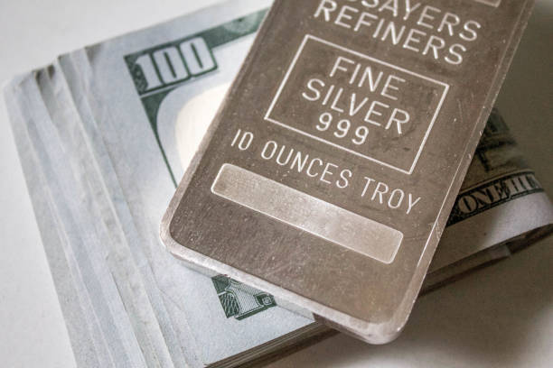 istock 10 Ounce Silver Bar Over Stack of Hundred Dollar Bills 661221898