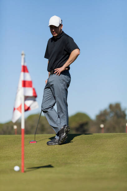 istock Man playing golf standing straight looking at golf ball while legs crossed 661248534