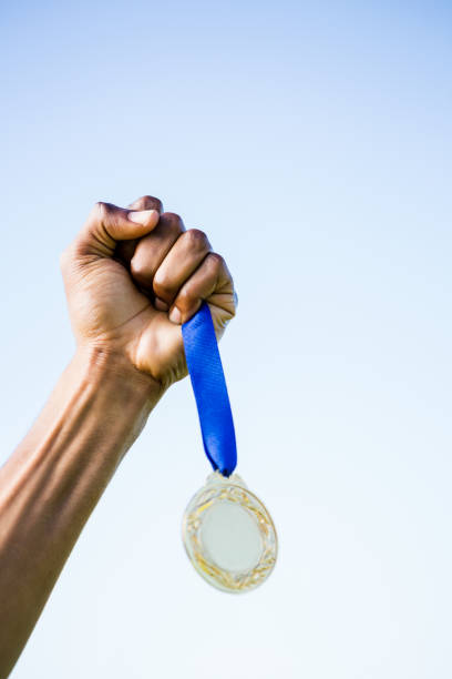 Athlete hand holding gold medal after victory Determined relay athlete running with baton running track relay photos stock pictures, royalty-free photos & images