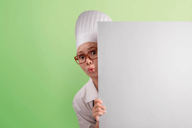 istock Funny asian woman chef peeking from behind blank copyspace 661320180