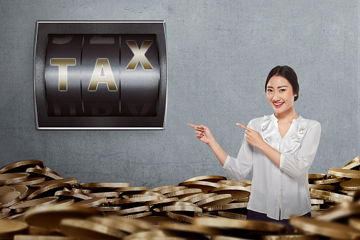 Young asian business woman showing tax time sign in counter digit at wall