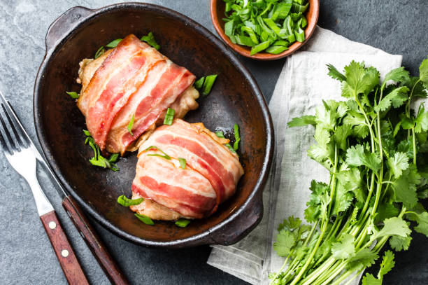 istock Baked chicken wrapped in bacon in clay bowl. Top view 661370700