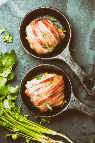 istock Baked chicken wrapped in bacon on cast iron pans. Top view 661370708