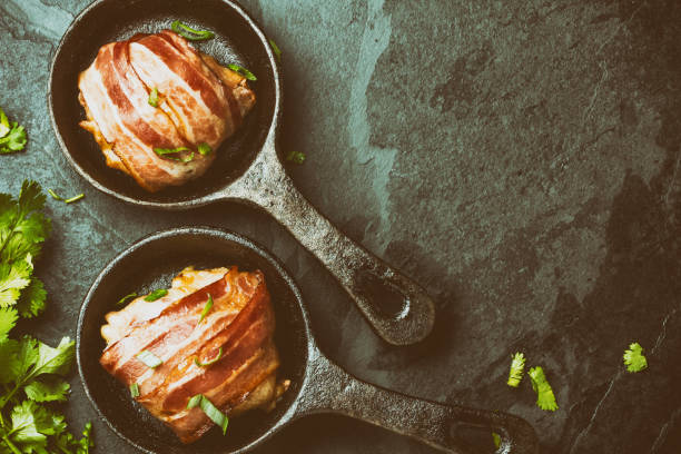 istock Baked chicken wrapped in bacon on cast iron pans. Top view 661370732