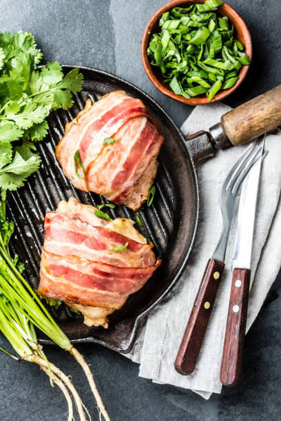 istock Fried chicken wrapped in bacon on cast iron grill pan. Top view 661370734