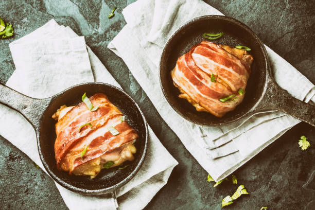 istock Baked chicken wrapped in bacon on cast iron pans. Top view 661370738