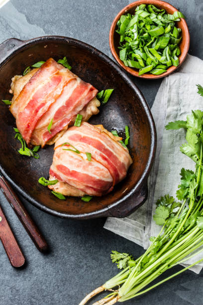 istock Baked chicken wrapped in bacon in clay bowl. Top view 661370744