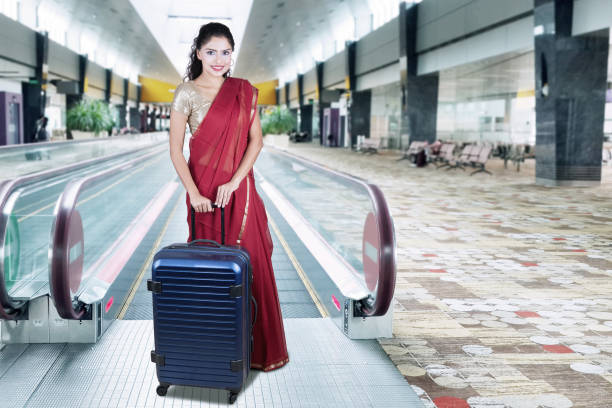 istock Indian woman holds suitcase on escalator 661380160