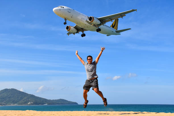 man jumps in front of airplane at the beach