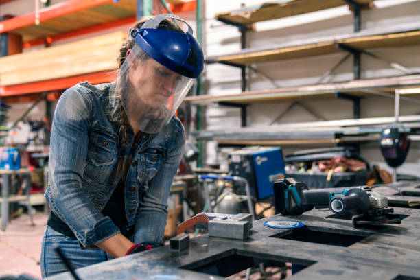 Woman tightening a vice to secure metal in place Female welder working in her workshop using an angle grinder. Los Angeles, America. October 2016 welding helmet stock pictures, royalty-free photos & images